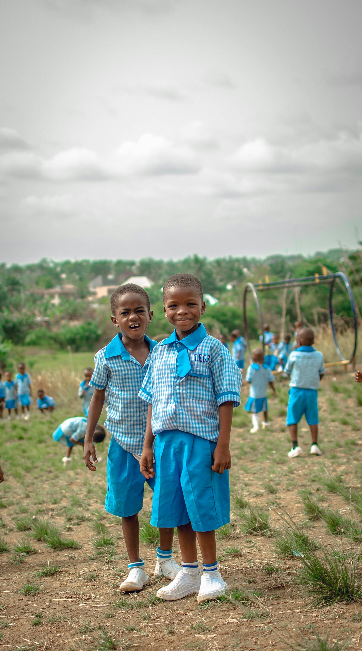 Happy children in blue uniforms enjoying a school day outdoors in Ishiagu, Nigeria.